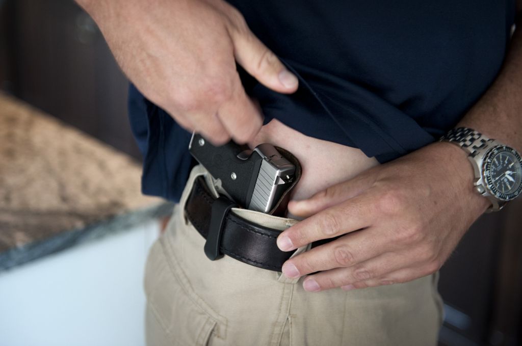 person showing a gun tugged into his pants