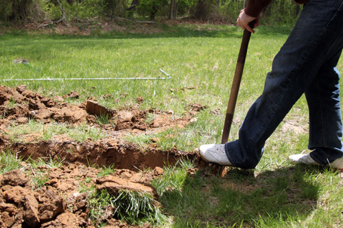 man digging hoe for patio with a shovel