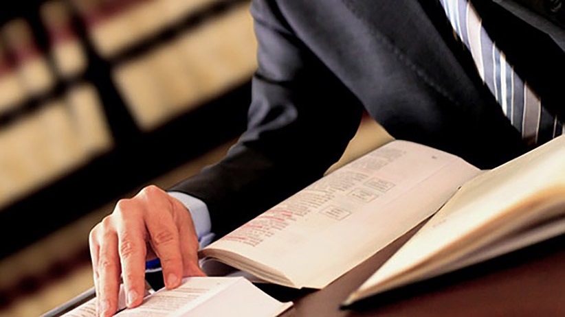 person in suit reading several books