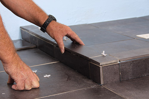 man tiling the floor dark tile