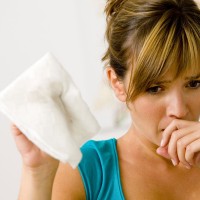 woman with a paper napking sneezing