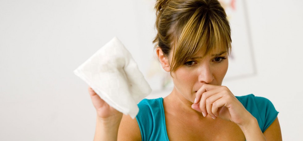 woman with a paper napking sneezing
