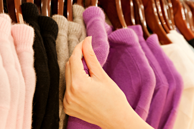 Hand touching cashmere sweater on clothing rack