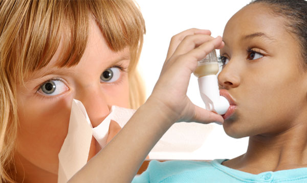 girl sneesing and other girl using an inhaler