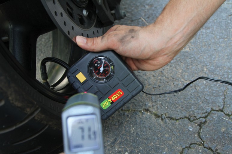 man checking pressure in motorcycle tires