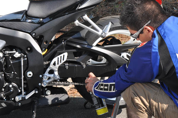 man spray-lubricating motorcycle chain
