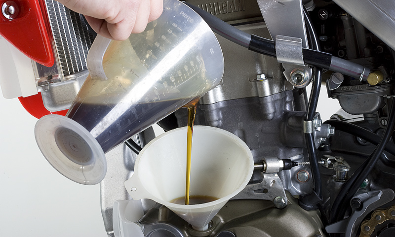 man adding oil to mortorcycle