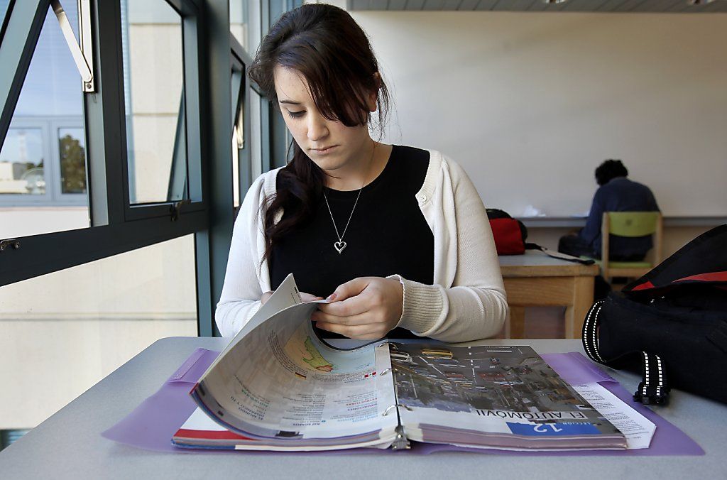 young woman at the desk reading foreign language textbook