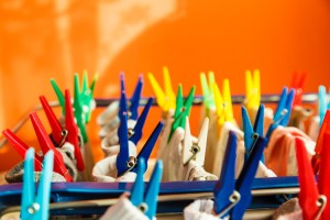 Housework concept. Closeup clothes hanging to dry on a laundry line with colorful pegs clips indoor