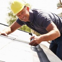 man in yellow hetmet installing roof shingles