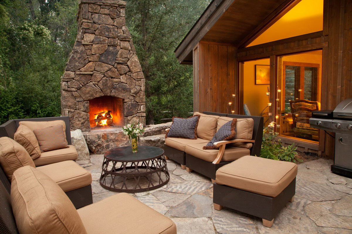 outdoor fireplace near the house with soft furniture on the patio