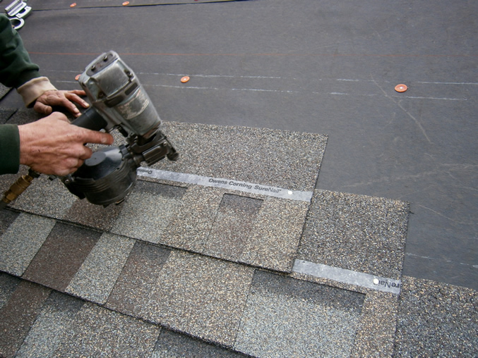 man nialing the shingles to the roof