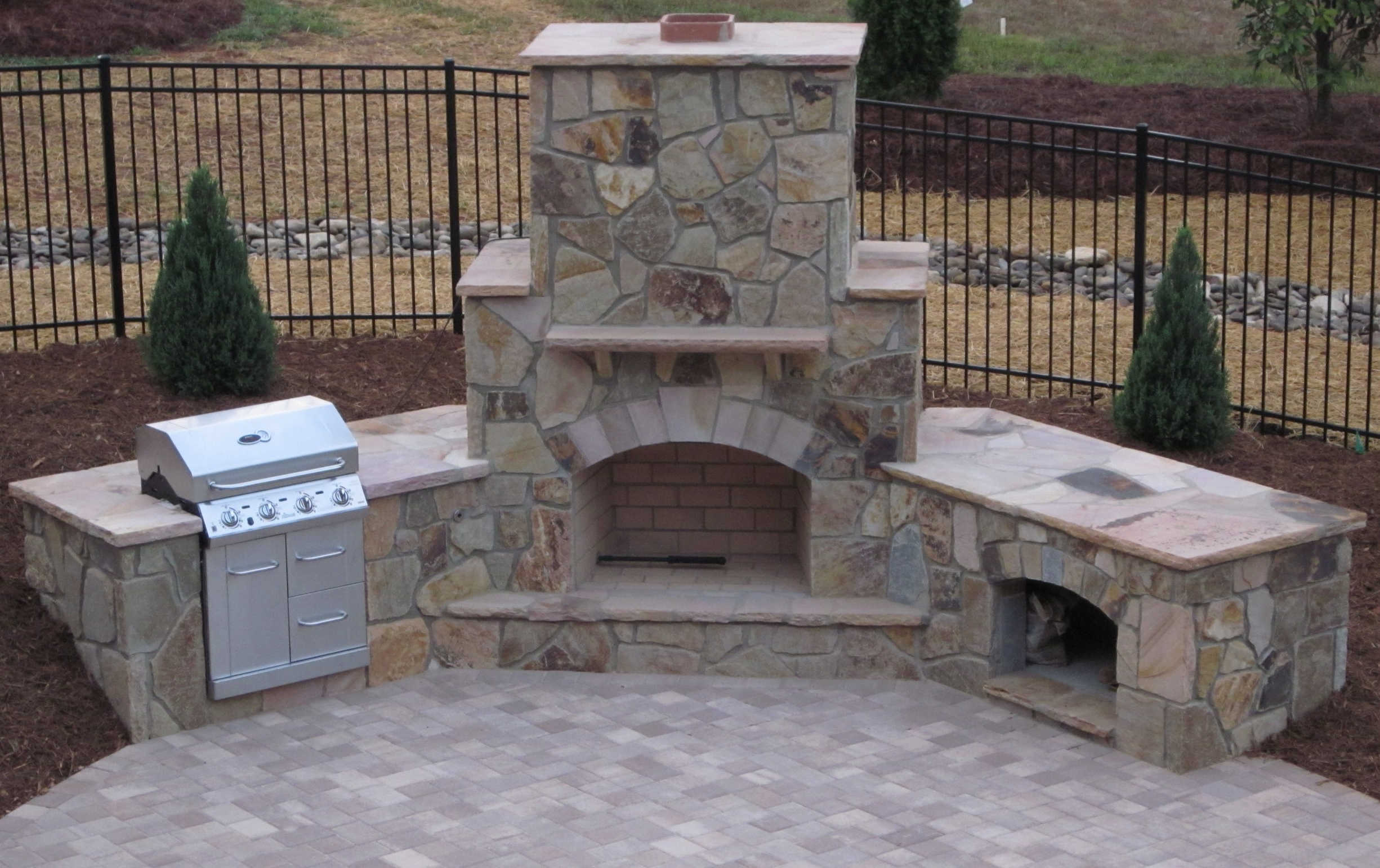 stone fireplace with a grill and wood box