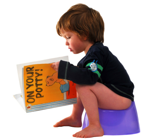 boy reading book while sitting on potty