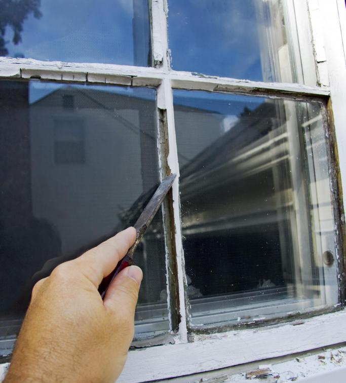 man scraping the window before window pane replacement