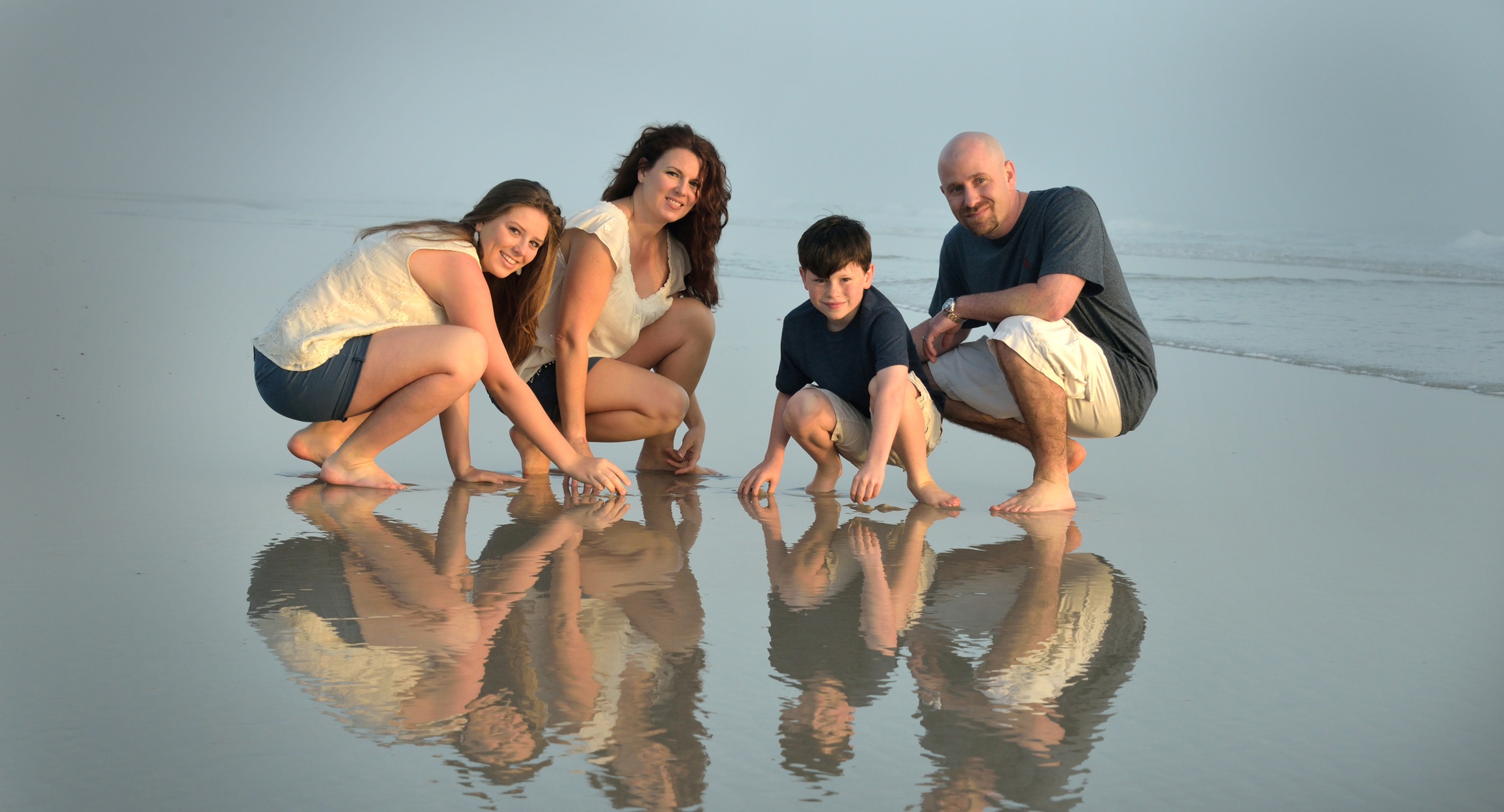 family photo reflection in the water on the beach