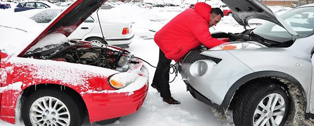 man trying to jump start a car in winter
