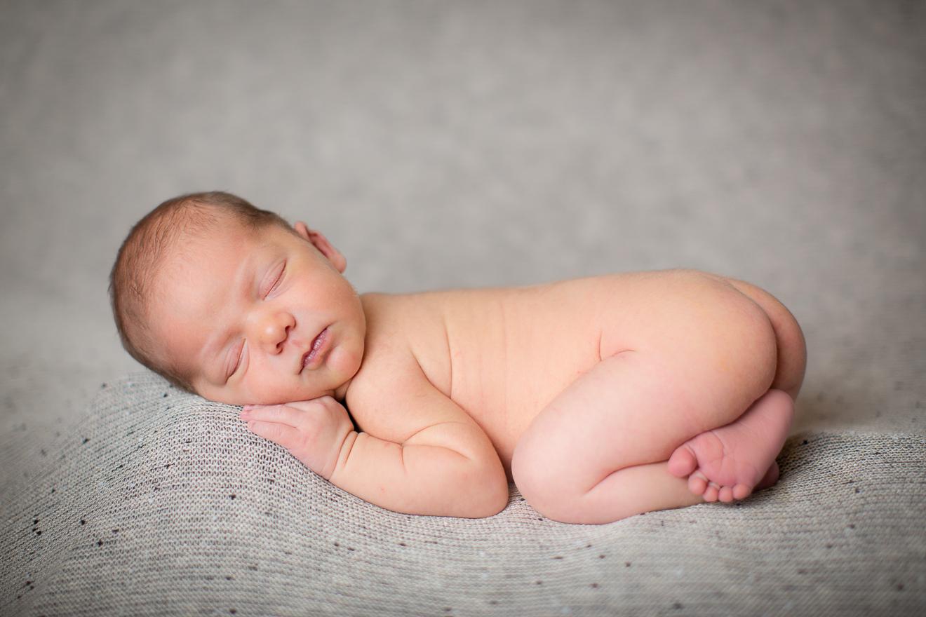 naked newborn baby sleeping on his tummy