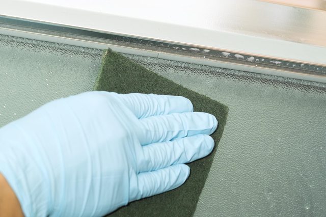 hand in rubber gloves cleaning frosted window glass