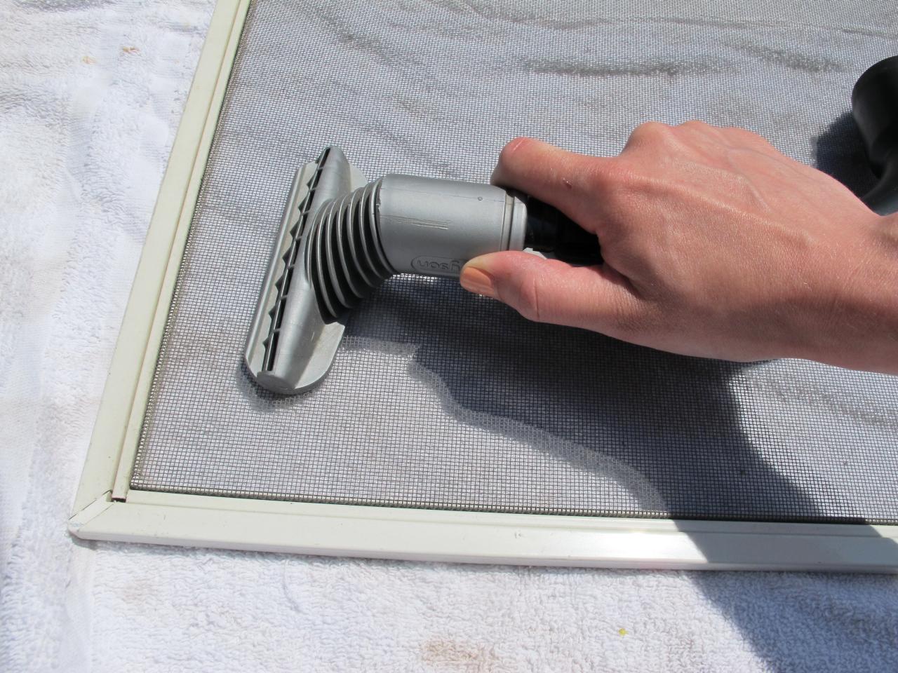 man vacuuming window screen