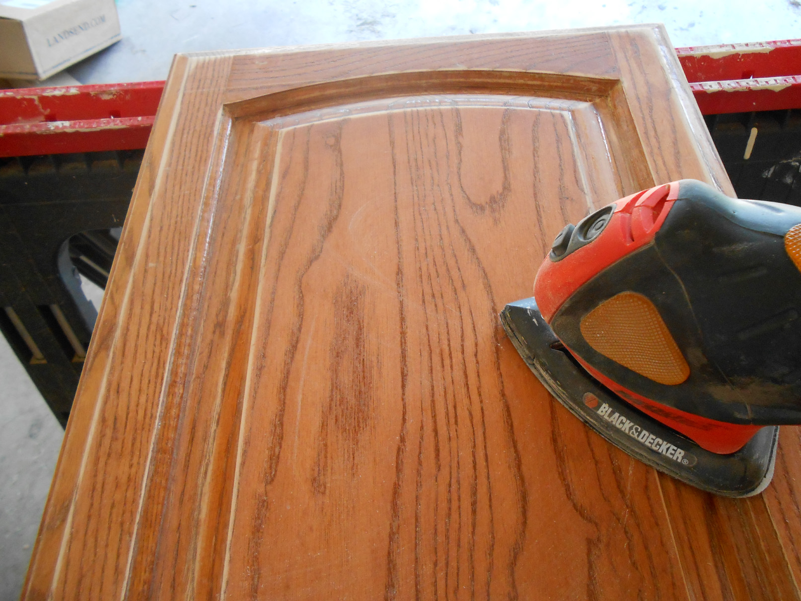 man sanding a door of a kitchen cabinet