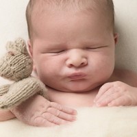 newborn sleeping holding a teddy bear