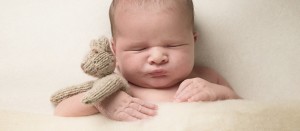 newborn sleeping holding a teddy bear