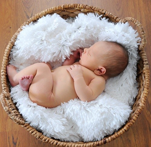 newborn sleeping on fluffy blanket in a basket