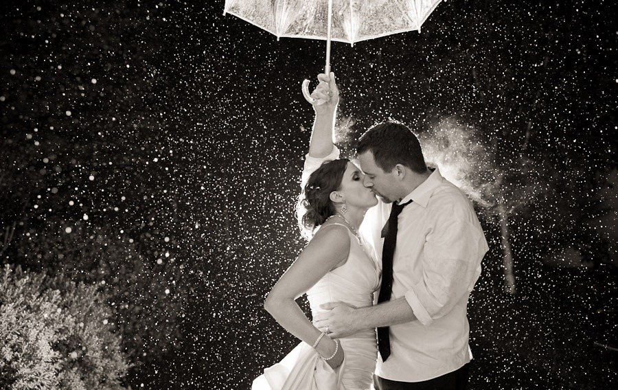 newlyweds under the downpour rain kissing