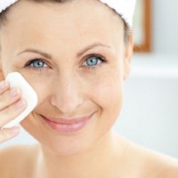 woman with a towel on her head cleansing her skin