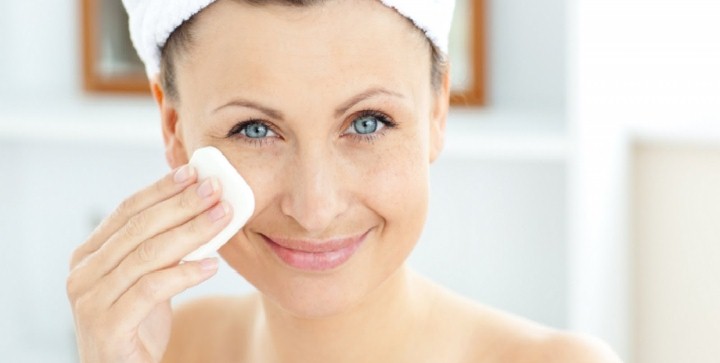 woman with a towel on her head cleansing her skin