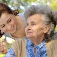 woman caregiver walking with an elderly woman in a wheelchair