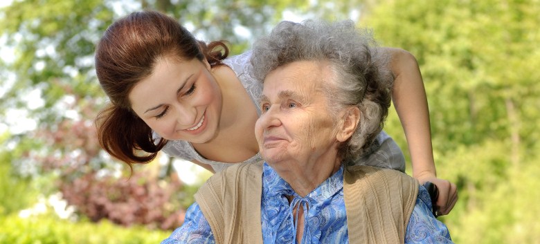 woman caregiver walking with an elderly woman in a wheelchair
