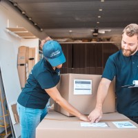 Two people checking the delivery information on the packages at the warehouse