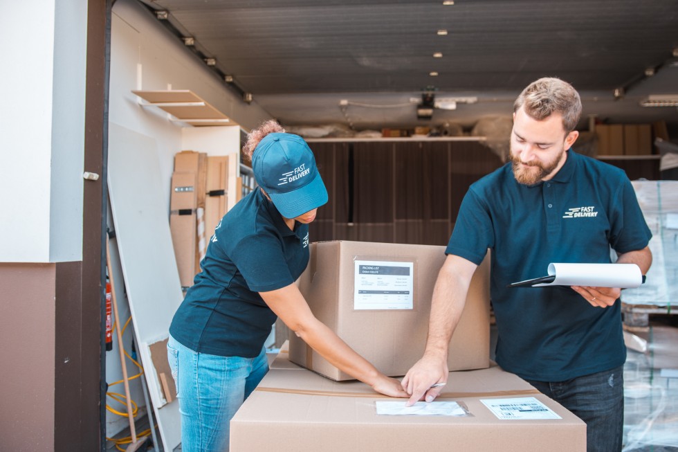 Two people checking the delivery information on the packages at the warehouse
