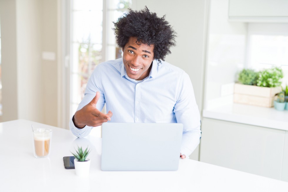 African American business man working using laptop very happy pointing with hand and finger