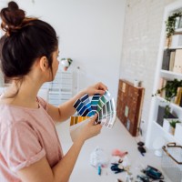 Young woman during reconstruction of apartment, holding color chart and choosing the right color for the wall
