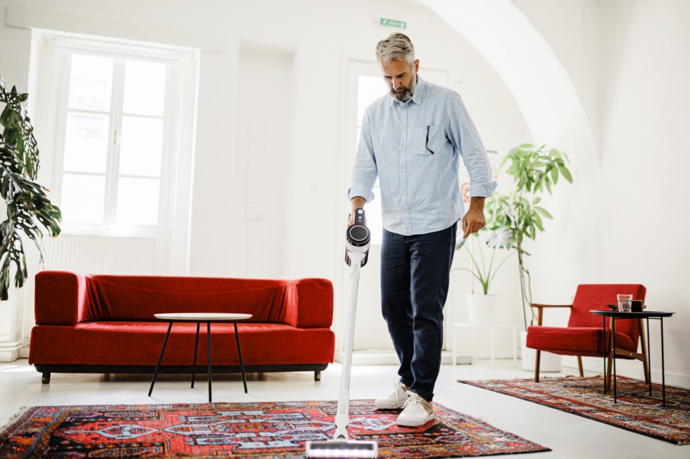 Man cleaning house with wireless vacuum cleaner