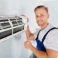 Smiling Male Electrician Gesturing Thumbs Up Near Air Conditioner