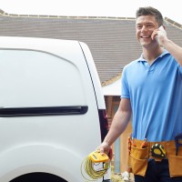 Electrician Standing Next To Van Talking On Mobile Phone